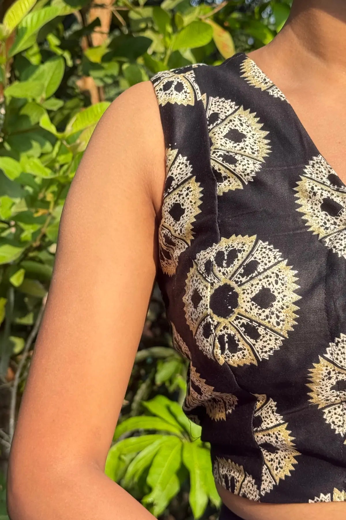 Side close-up of black handcrafted cotton blouse showcasing detailed block print fabric and sleeveless cut, photographed outdoors