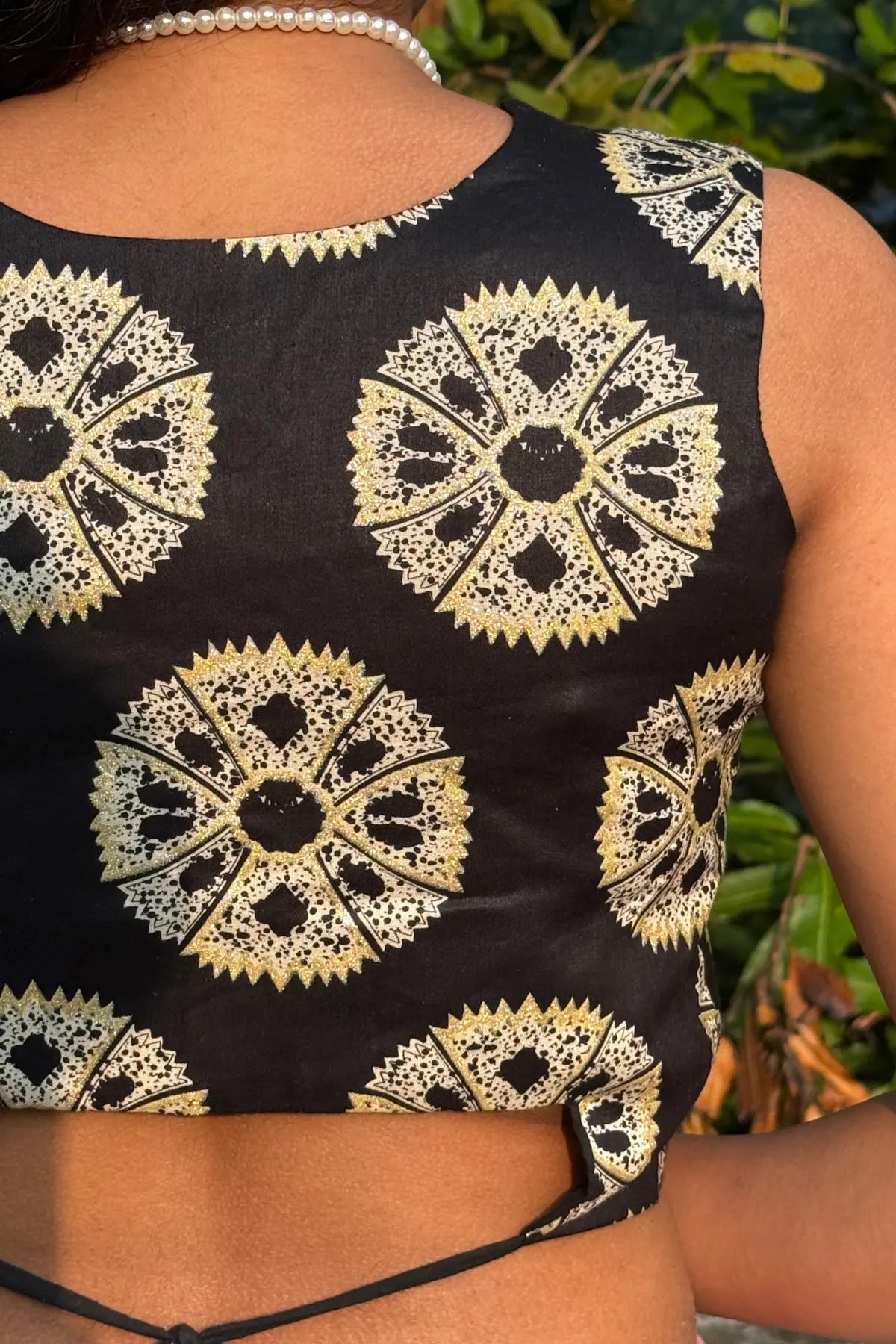 Back view of model wearing black handcrafted cotton blouse with traditional block print, styled outdoors in natural sunlight