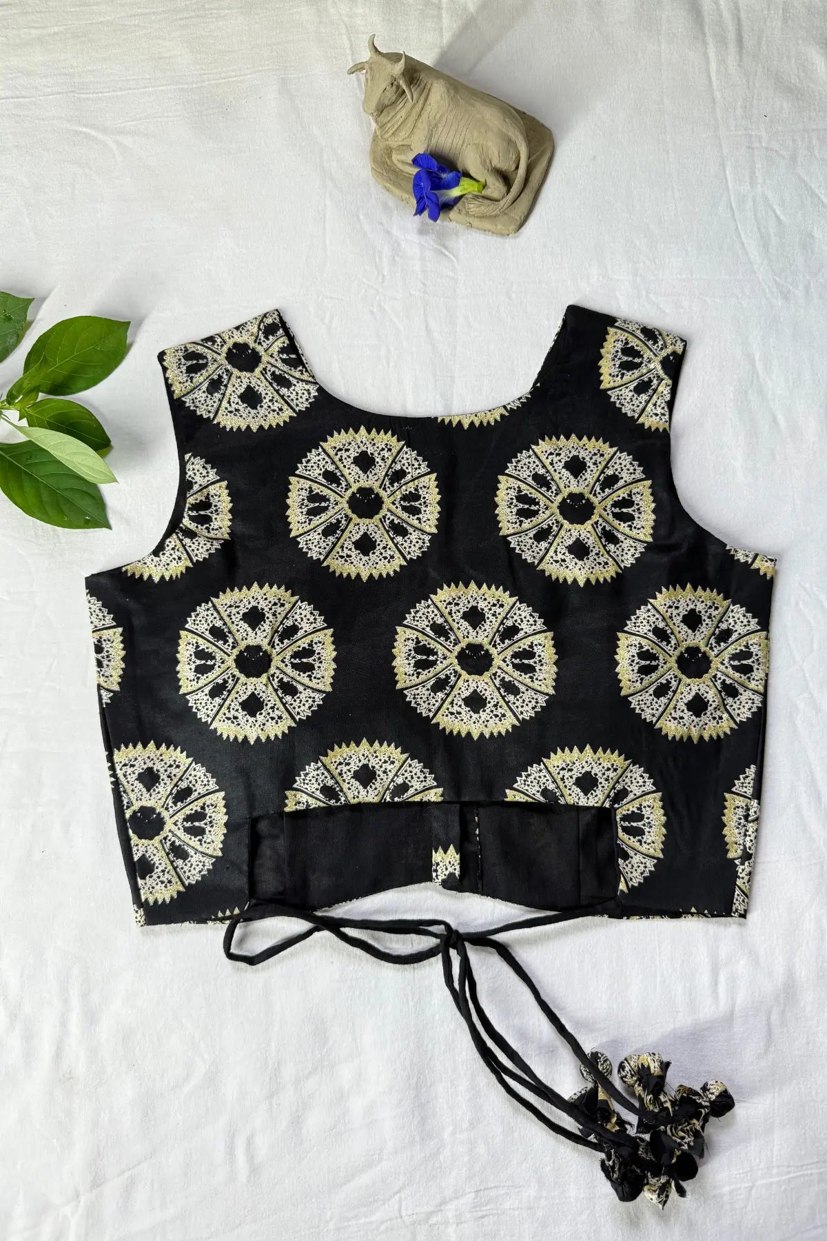 Back view of handcrafted black cotton blouse with block print pattern and tie-up dori detail, flat lay on white background
