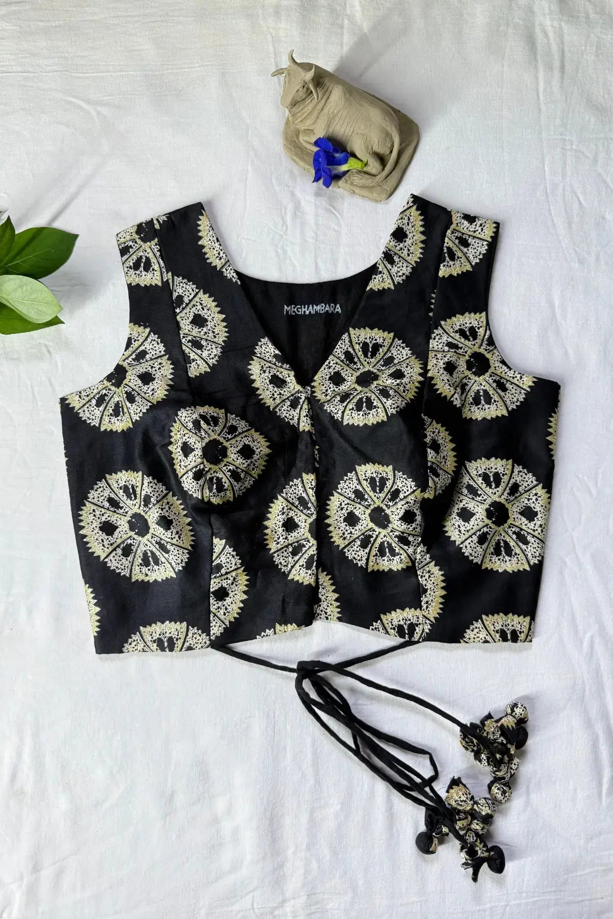 Front view of handcrafted black cotton blouse with traditional block print, sleeveless design and V-neck, laid flat on white fabric background
