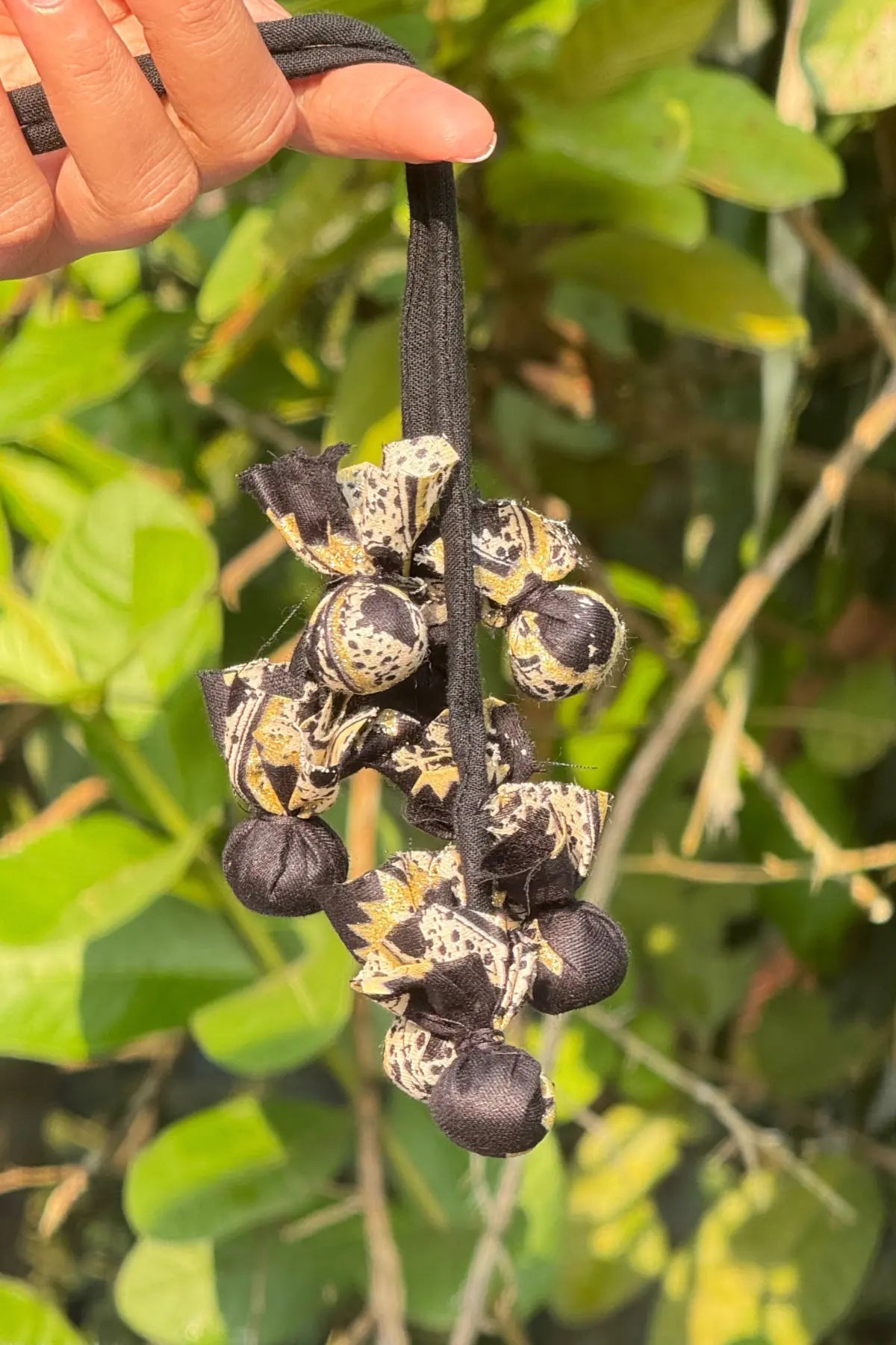 Handcrafted black cotton blouse tie-up dori with printed fabric tassels, photographed outdoors in natural light