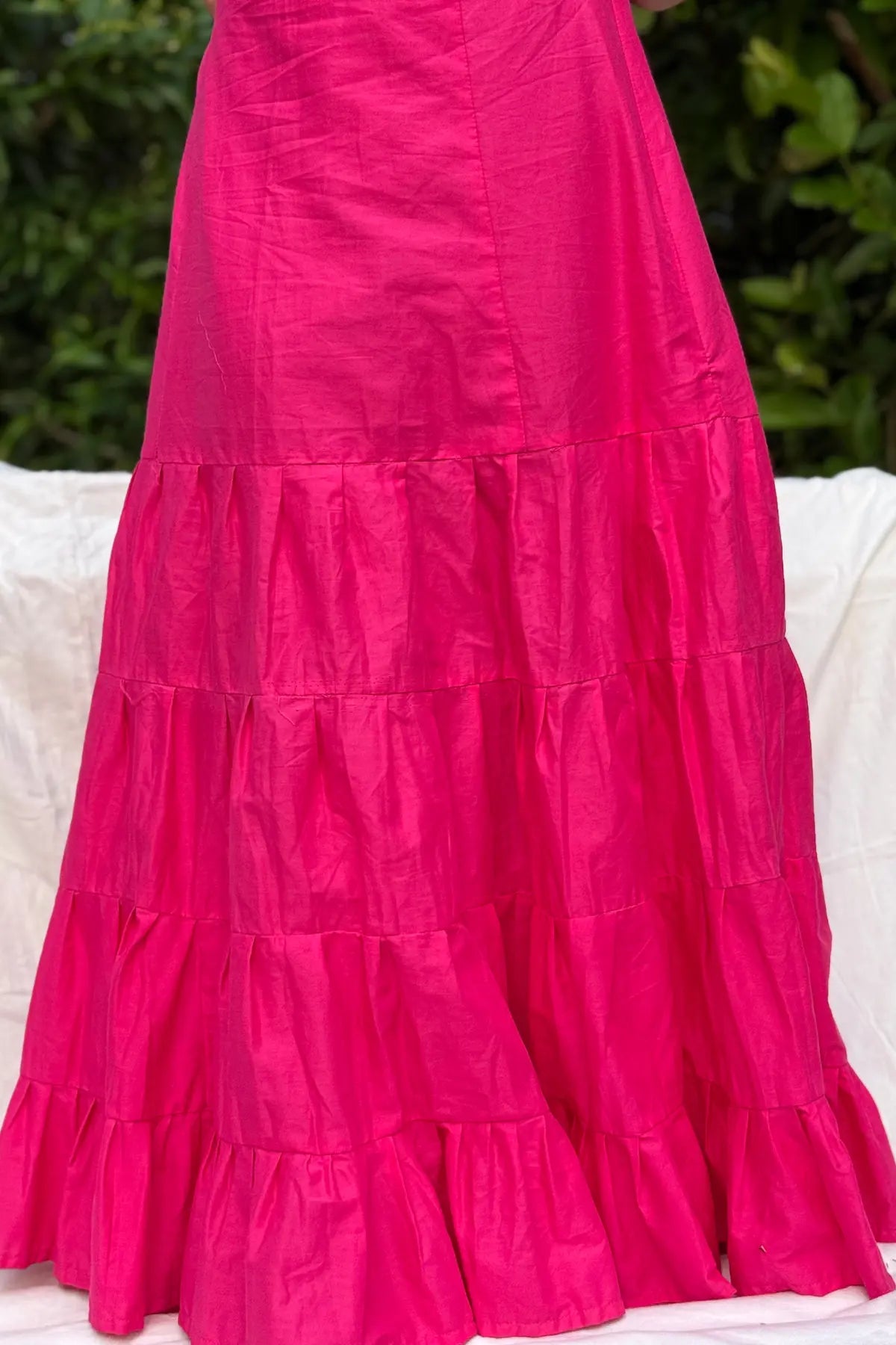 Bright pink cotton petticoat worn by a model, featuring a flared silhouette with multiple gathered tiers for comfortable volume.