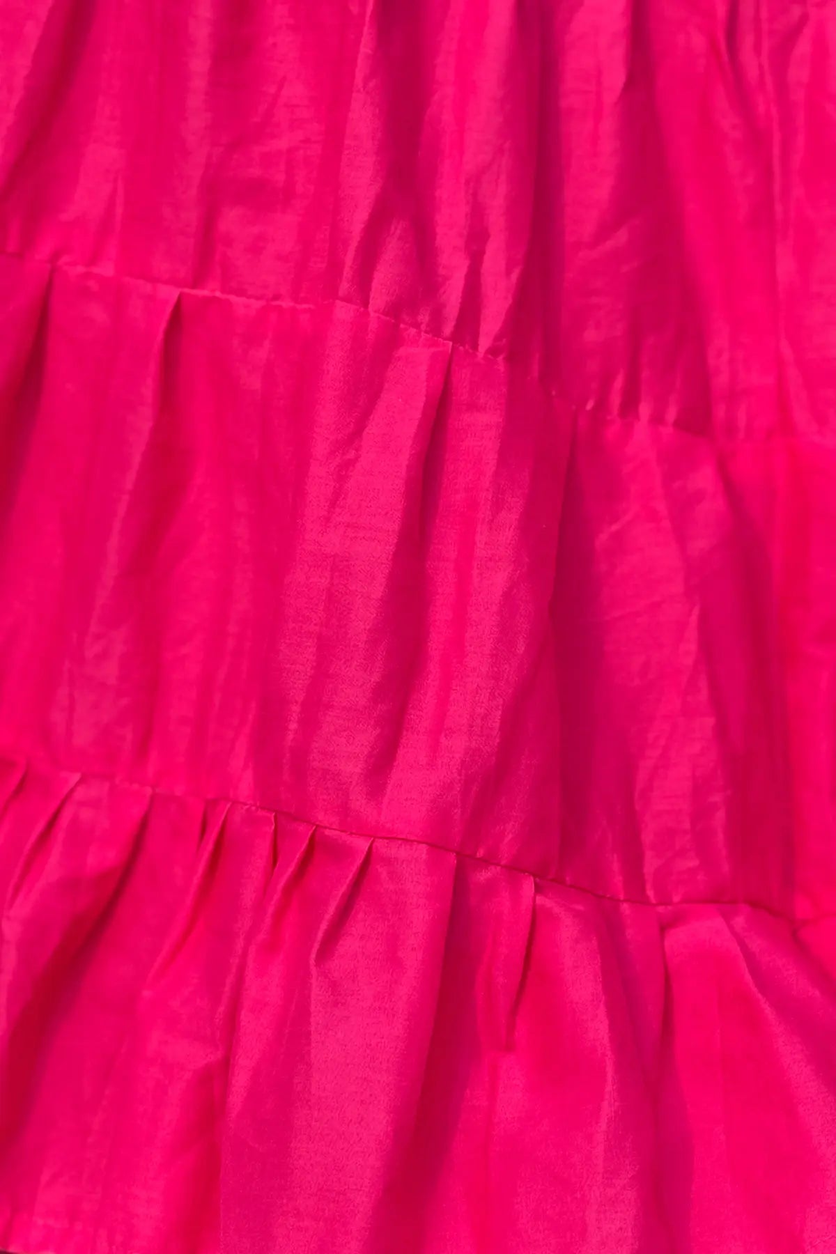 Side angle of bright pink cotton petticoat highlighting the gathered tier construction and flowing drape of the fabric.