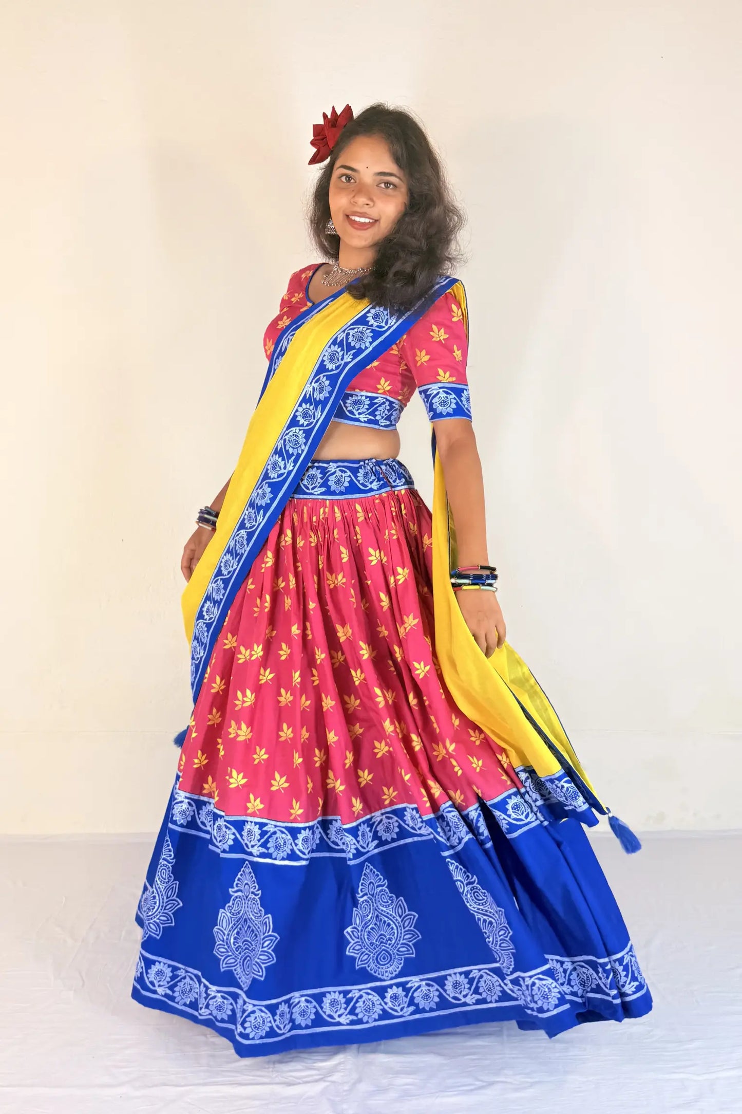 Woman wearing a colorful traditional outfit with a yellow and blue Gopi Dress on a white background