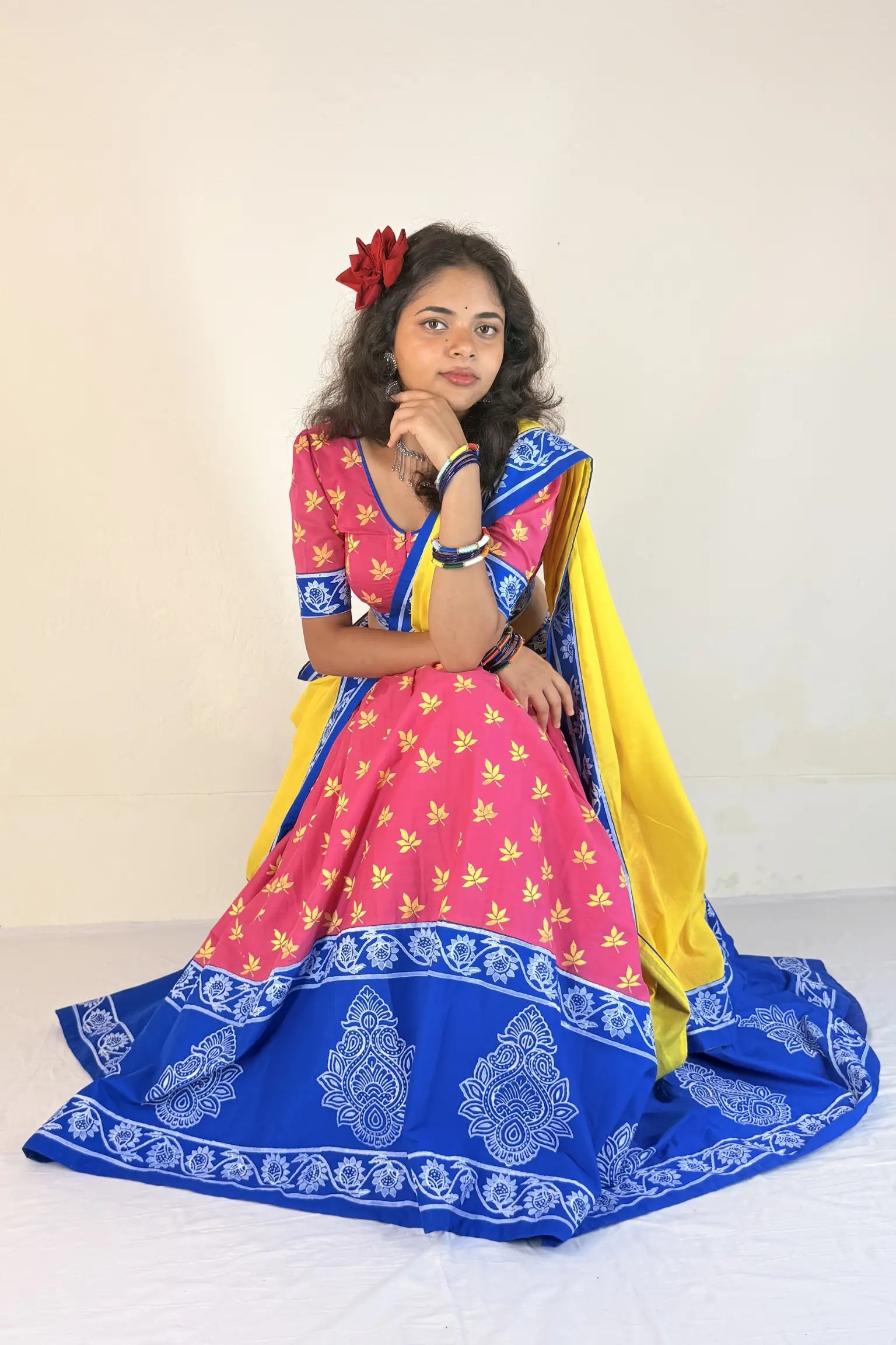 Woman wearing a colorful traditional outfit with a pink and blue Gopi Dress on a white background