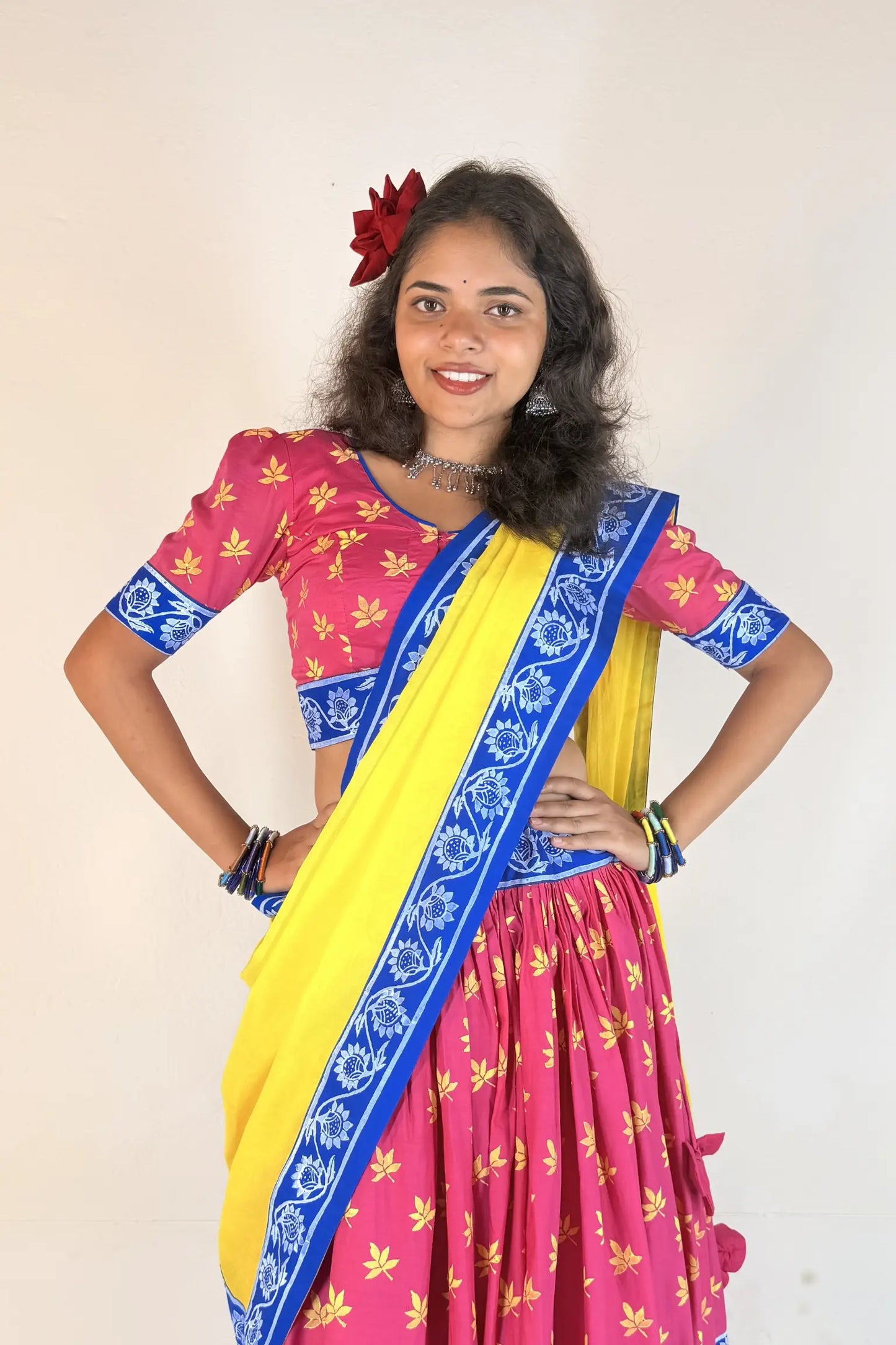 Woman wearing a colorful Gopi Dress with a pink blouse and yellow skirt on a plain background