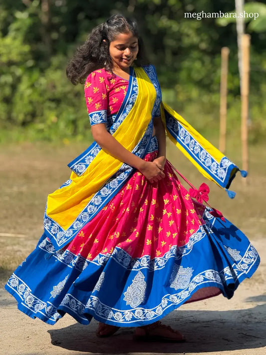 Woman in a colorful gopi dress with pink, yellow, and blue patterns outdoors.
