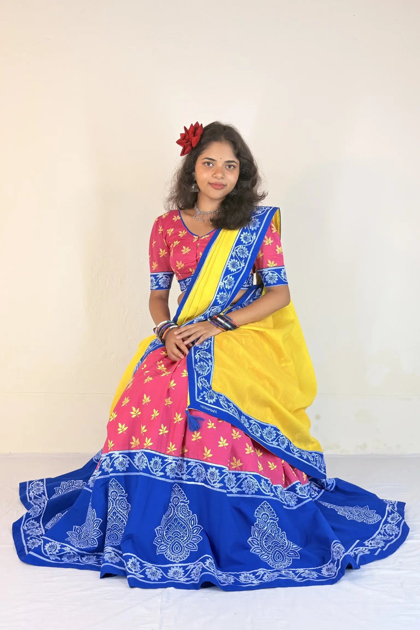 Woman wearing a colorful Gopi Dress with pink, yellow, and blue patterns on a white background