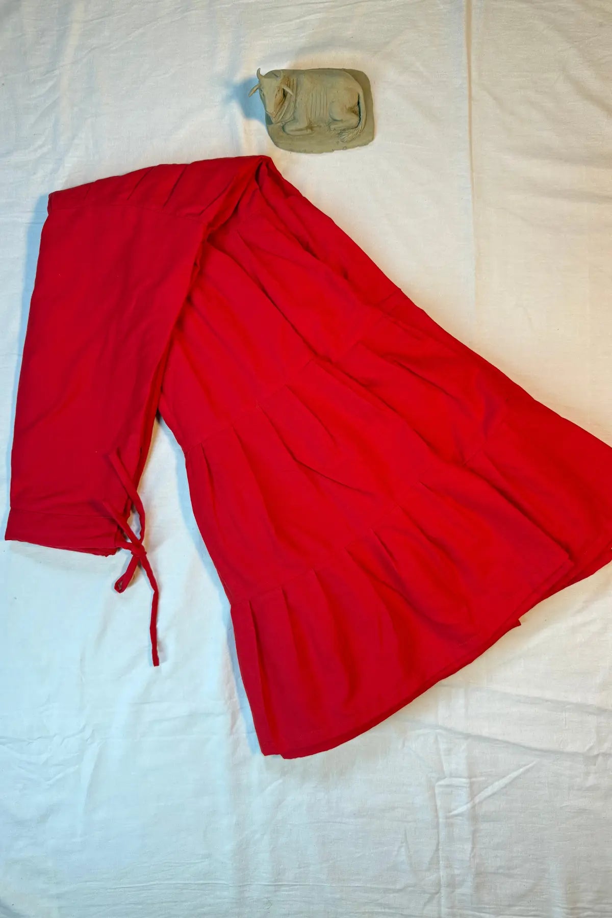 Red cotton petticoat underskirt laid flat on white background with adjustable side tie and flared design