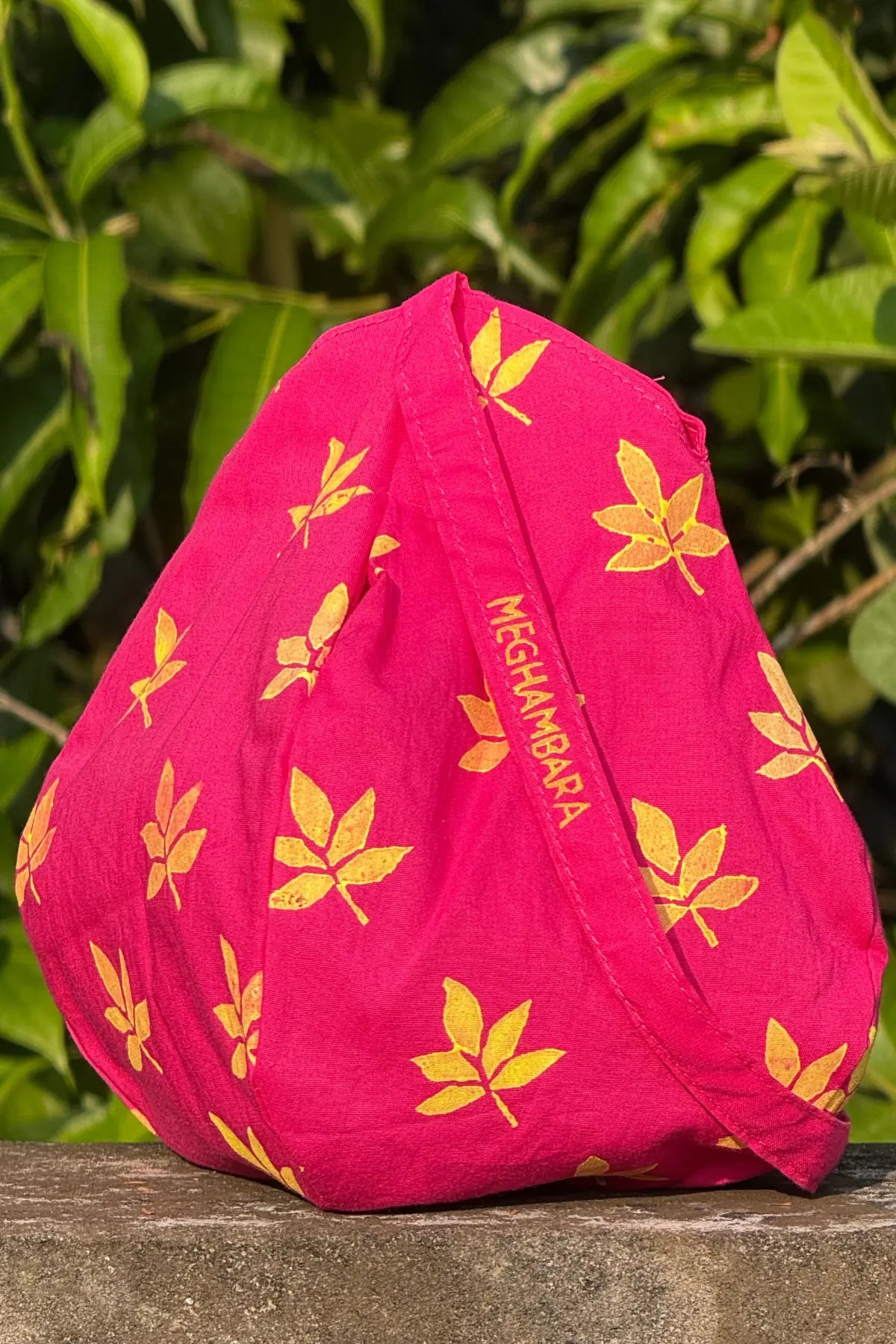 Handcrafted pink cotton japa mala bag with yellow floral block print and Meghambara branding strap, eco-friendly spiritual accessory