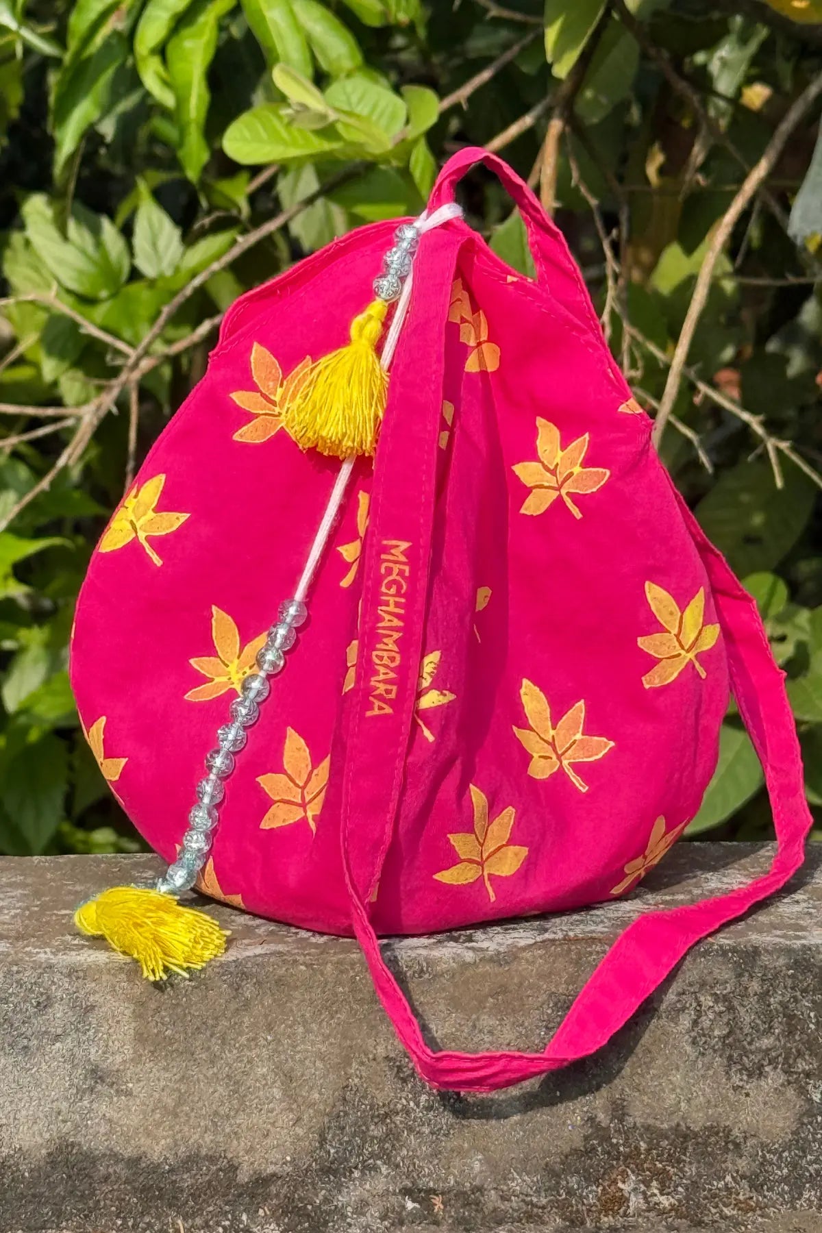 Pink handcrafted japa mala bag featuring yellow leaf motif block print, drawstring closure and decorative tassel by Meghambara
