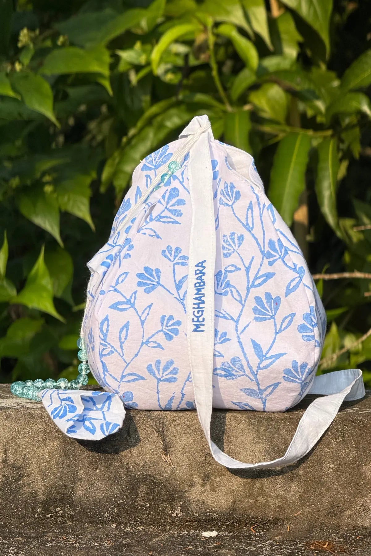 Handcrafted white cotton japa mala bag with blue floral block print and long strap, eco-friendly spiritual accessory by Meghambara
